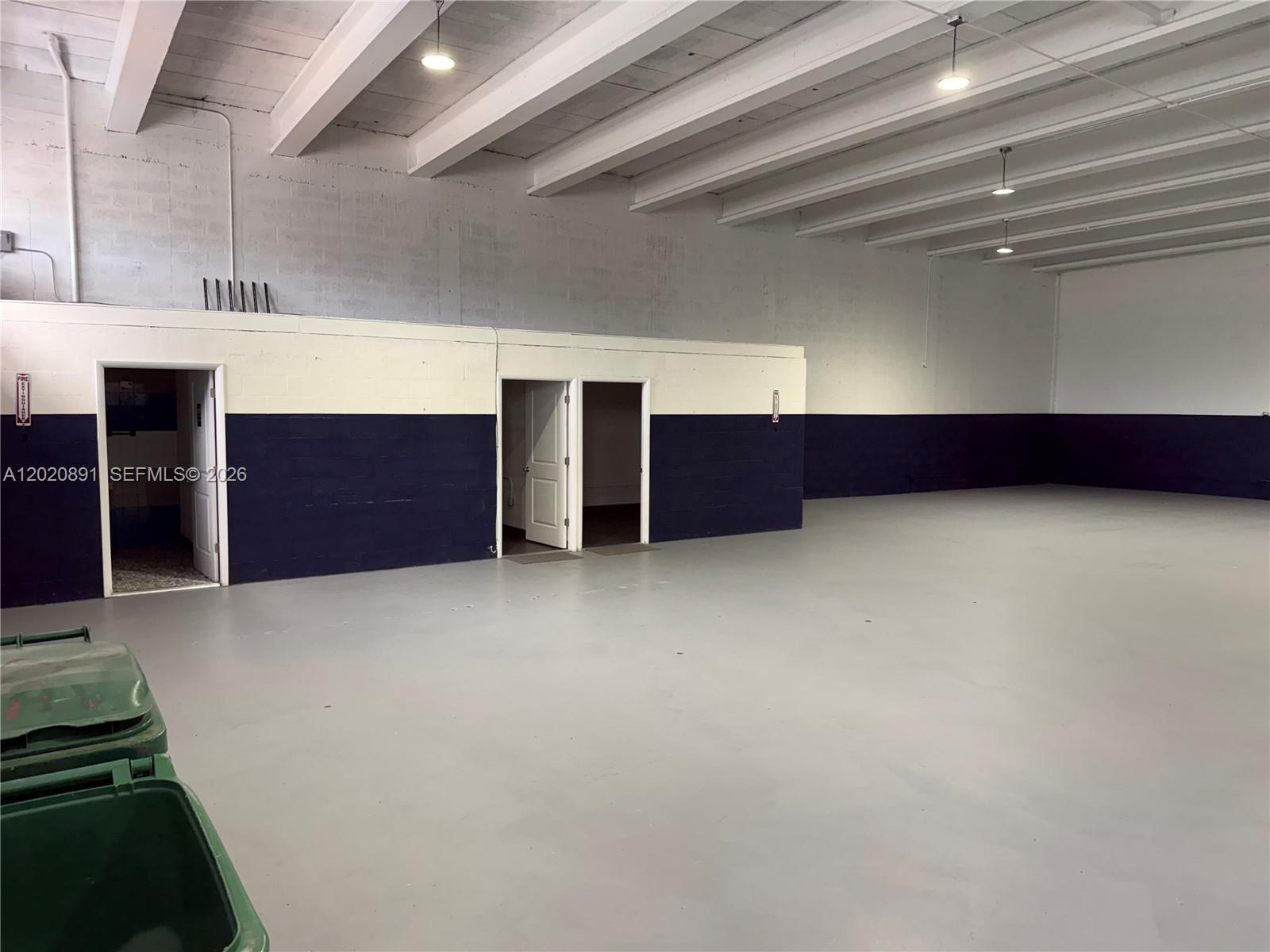 An empty warehouse space features a gray concrete floor, white ceiling beams, and two-toned walls — 3911 NW 25 ST, Miami FL 33142, MIAMI, FL