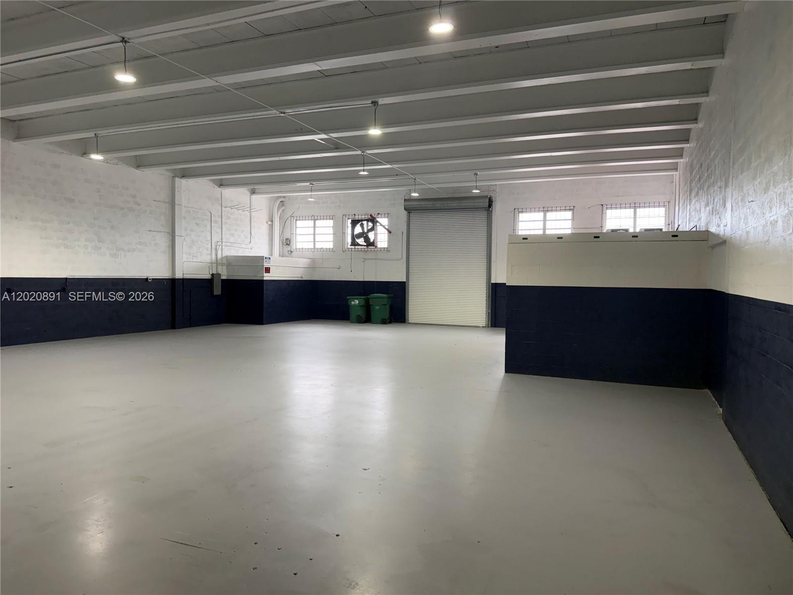 An empty industrial warehouse space features white and navy walls, concrete floors, and exposed beams — 3911 NW 25 ST, Miami FL 33142, MIAMI, FL