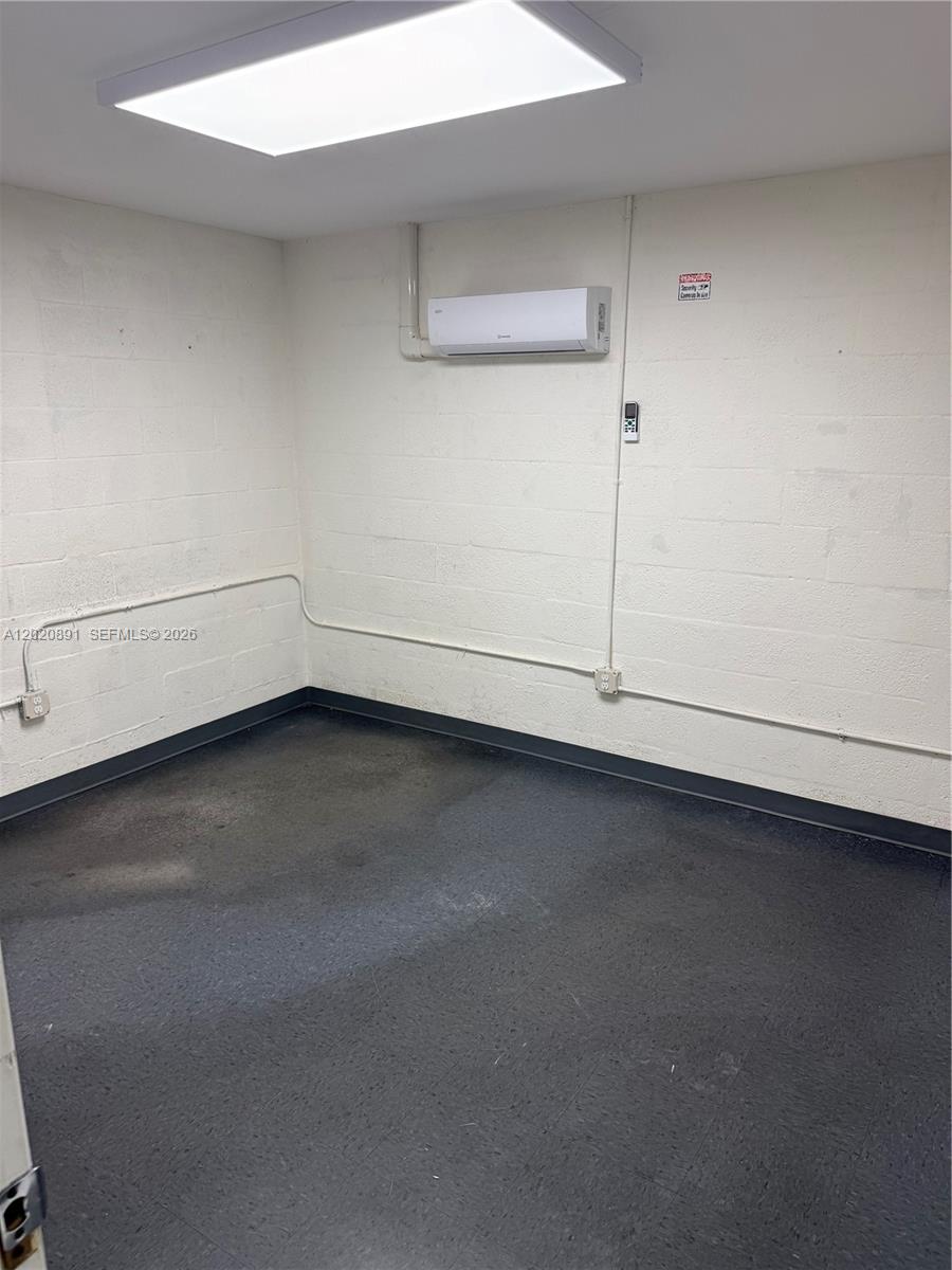 This room features white painted cinder block walls, a mini-split air conditioner, and dark flooring — 3911 NW 25 ST, Miami FL 33142, MIAMI, FL