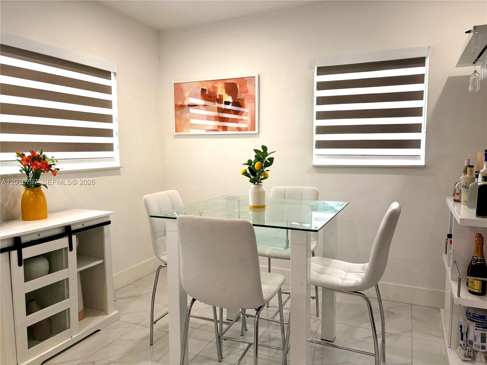 A dining area features a glass-top table, white chairs, and two windows with striped shades — 6515 SW 20th Ct, Miramar FL 33023, MIRAMAR, FL