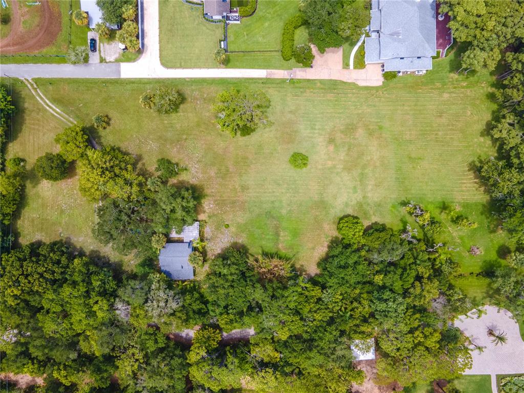 An aerial view shows a large grassy lot with a house, trees, and paved driveway — 1133 BELLA LAGO COVE, WINTER PARK, FL