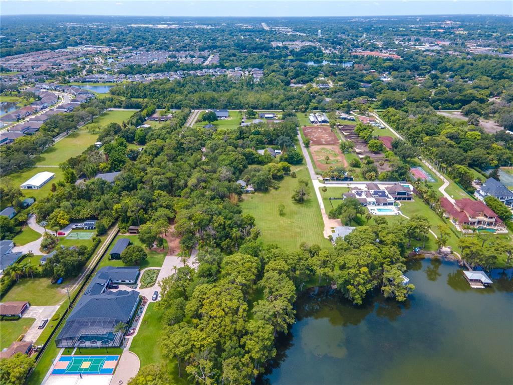 An aerial view shows several large residential properties with pools and a lake — 1133 BELLA LAGO COVE, WINTER PARK, FL