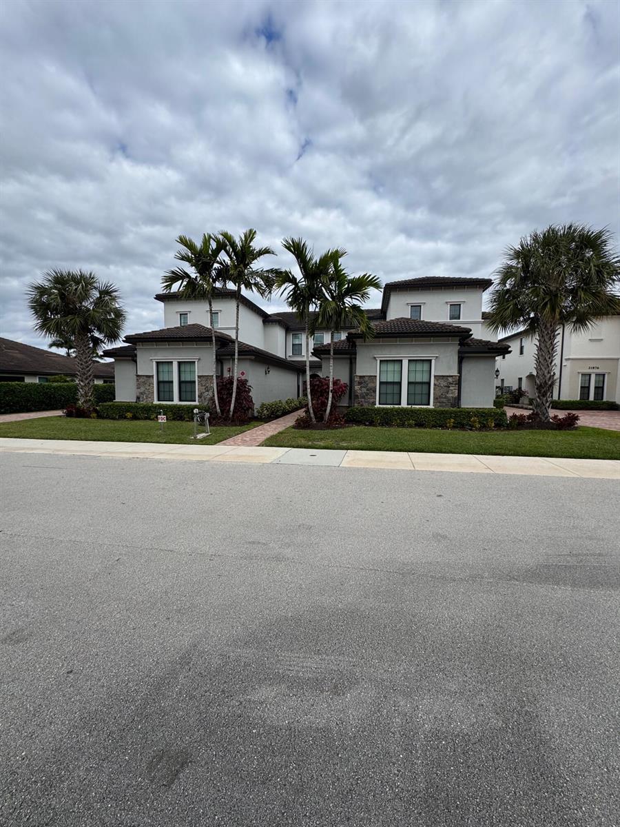 A two-story residential building with a gray stucco exterior, stone accents, and palm trees — 21872 Canadensis Circle # 202, Boca Raton FL 33428, BOCA RATON, FL
