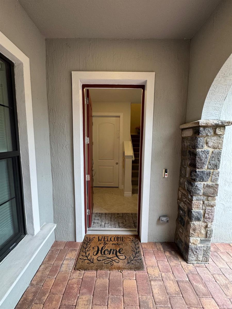 A front entryway with a stone pillar, brick paver porch, and a welcome mat — 21872 Canadensis Circle # 202, Boca Raton FL 33428, BOCA RATON, FL