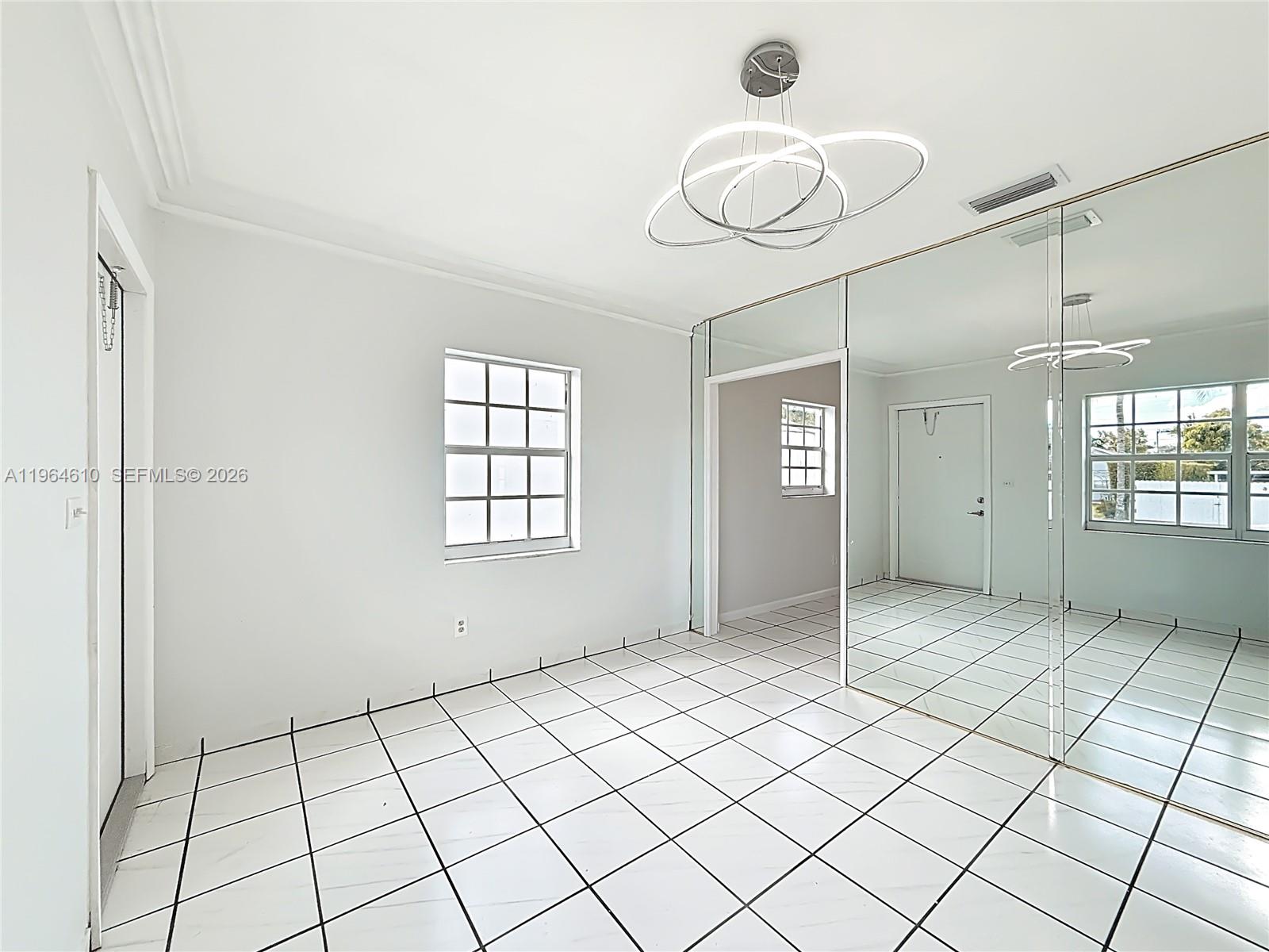 A room with white tiled floors, a modern light fixture, and a mirrored wall — 6819 SW 25th St, Miami FL 33155, MIAMI, FL