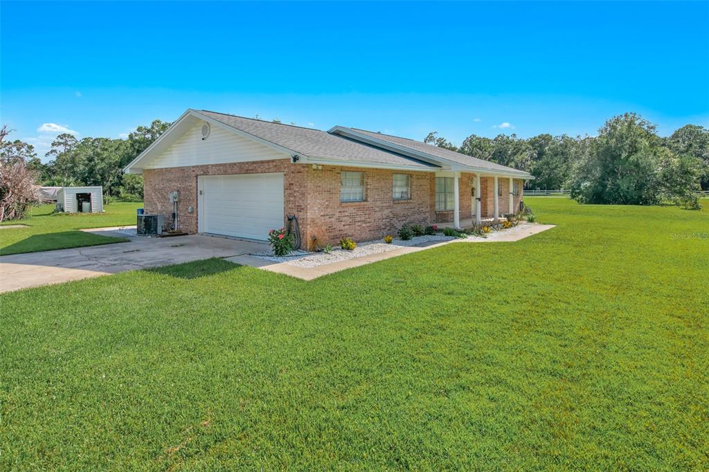 A single-story brick house with a two-car garage sits on a large, grassy lot — 2041 HALIFAX DRIVE, PORT ORANGE, FL