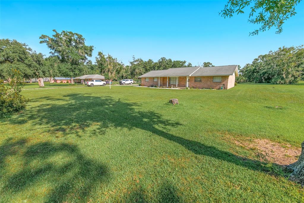 A single-story brick house sits on a large, grassy lot with several trees — 2041 HALIFAX DRIVE, PORT ORANGE, FL