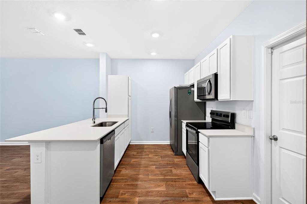 A kitchen features white cabinets, stainless steel appliances, and wood-look flooring — 871 RIVERTREE PLACE, MIDDLEBURG, FL