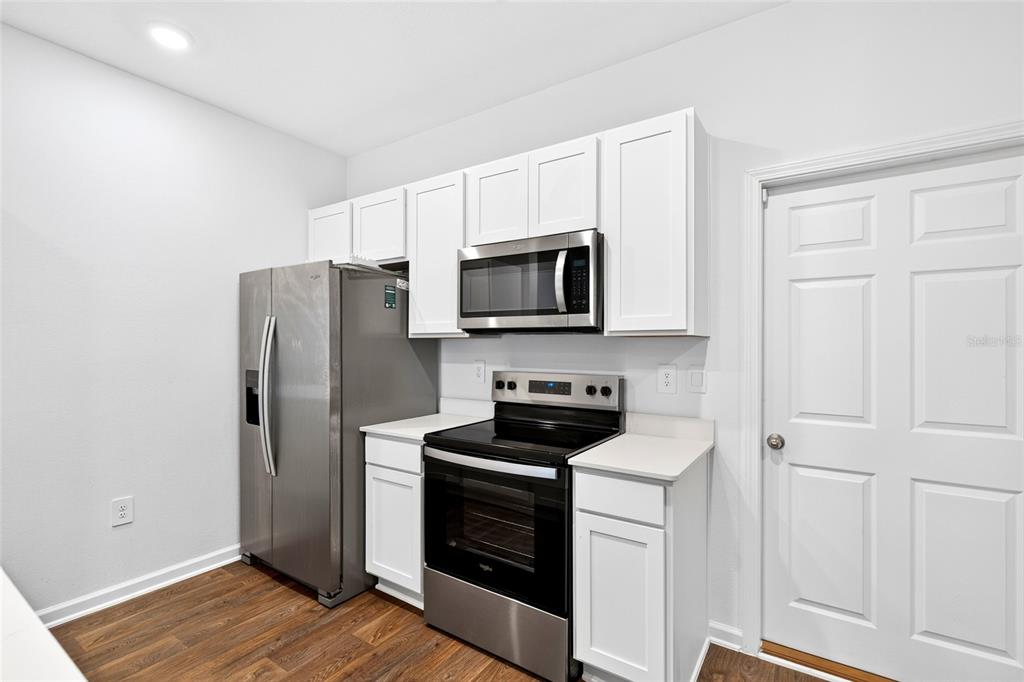 A kitchen island with a stainless steel dishwasher faces an open living area with wood floors — 871 RIVERTREE PLACE, MIDDLEBURG, FL
