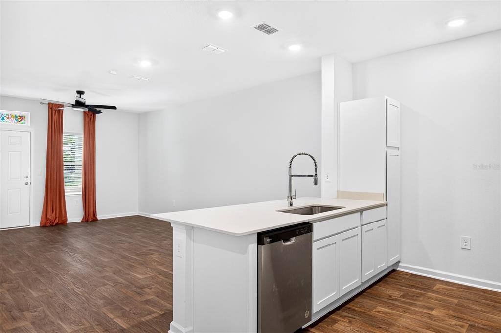 An empty room features wood-look flooring, white walls, a ceiling fan, and a front door — 871 RIVERTREE PLACE, MIDDLEBURG, FL