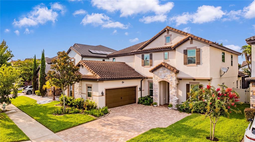 A two-story suburban house with a tiled roof, stone accents, and a paved driveway — 6443 SWANSON STREET, WINDERMERE, FL