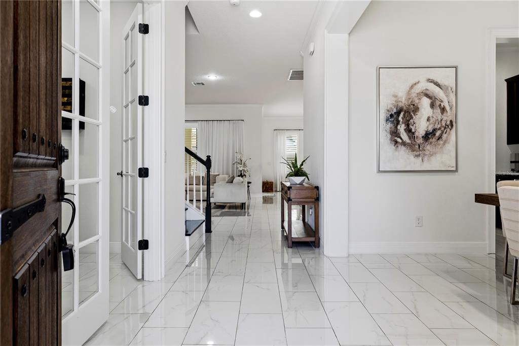 A bright entryway features white marble-look tile flooring, a wooden console table, and French doors — 6443 SWANSON STREET, WINDERMERE, FL