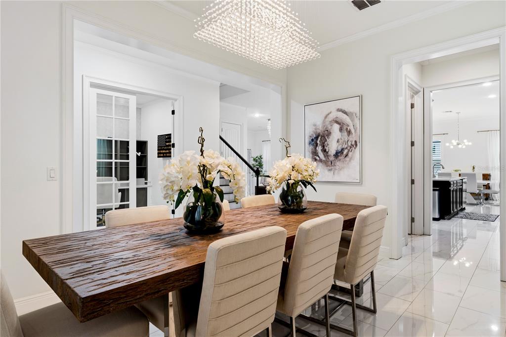 A dining room features a rustic wooden table, upholstered chairs, and a modern crystal chandelier — 6443 SWANSON STREET, WINDERMERE, FL