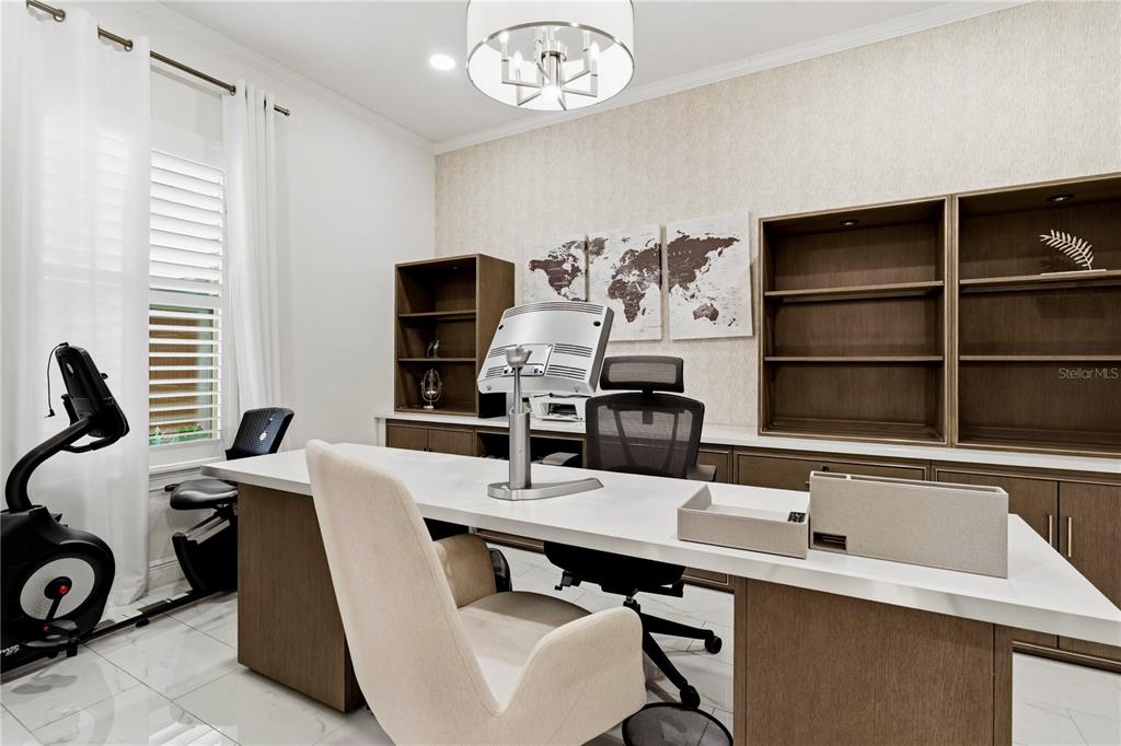 A home office features a white desk, a beige chair, built-in shelving, and a stationary bike — 6443 SWANSON STREET, WINDERMERE, FL
