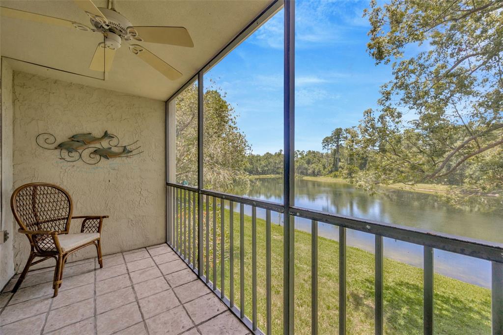 A screened-in patio with a wicker chair, ceiling fan, and a view of a lake — 3134 LAKE PINE WAY UNIT F2, TARPON SPRINGS, FL