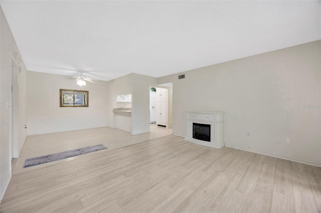 A living room with light wood-look flooring, a white electric fireplace, and a ceiling fan — 3134 LAKE PINE WAY UNIT F2, TARPON SPRINGS, FL