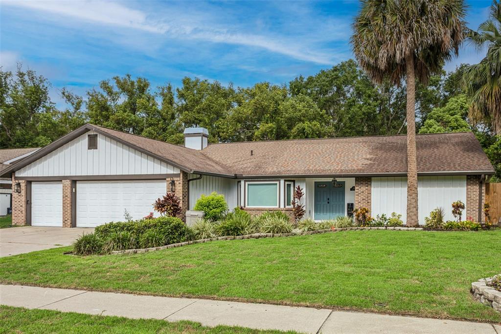 A single-story house with a white vertical-siding facade, brick accents, and a two-car garage — 1046 SYLVIA LANE, TAMPA, FL