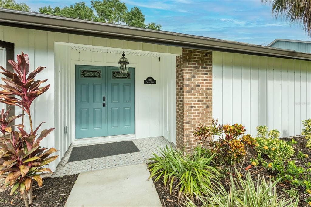 The exterior of a house features a teal double front door and a brick column — 1046 SYLVIA LANE, TAMPA, FL