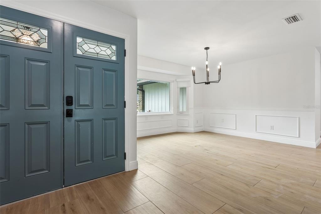 An entryway with a blue double door leads into a dining room with wood floors — 1046 SYLVIA LANE, TAMPA, FL