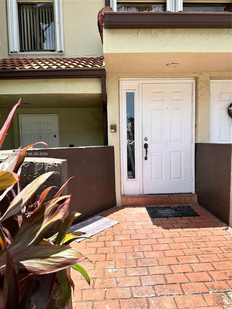 The exterior of a townhouse features a white front door and a brick walkway — 9607 SW 138th Ave, Miami FL 33186, MIAMI, FL