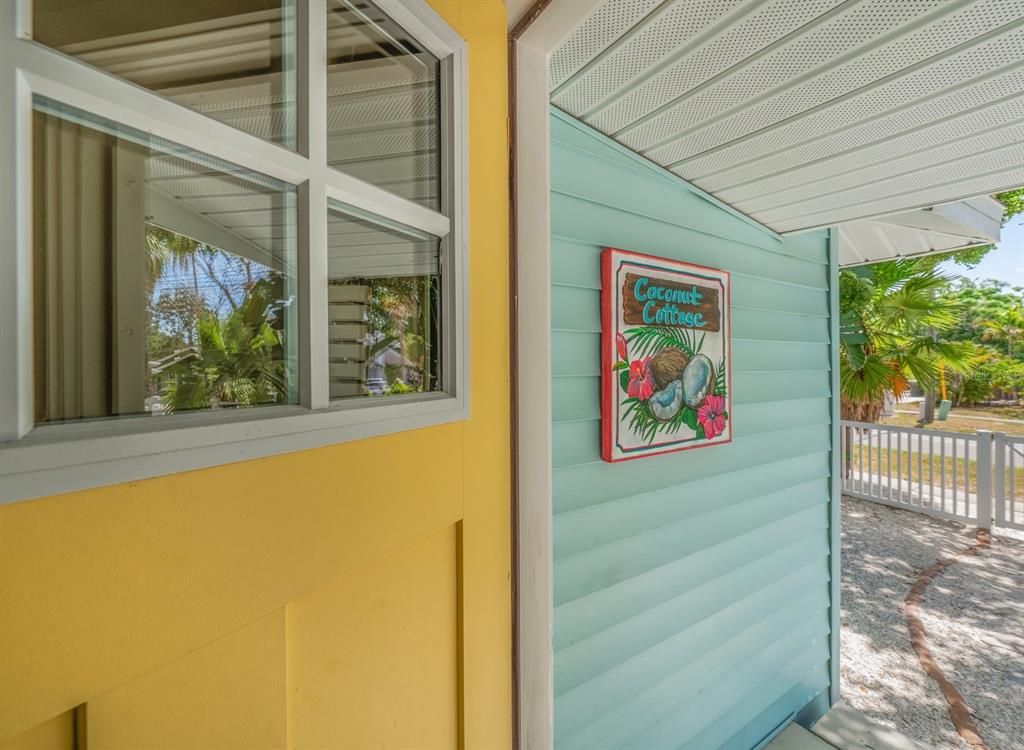 A yellow wall and a light blue exterior wall with a Coconut Cottage sign — 932 HIGHLAND AVENUE, DUNEDIN, FL