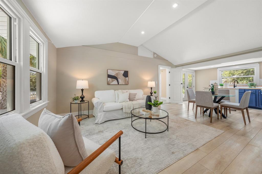 A bright living and dining area features a white sofa, glass coffee table, and wood-look flooring — 932 HIGHLAND AVENUE, DUNEDIN, FL