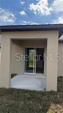 A covered concrete patio leads to a sliding glass door on the exterior of a house — 1629 TROPICAL OASIS AVENUE, PLANT CITY, FL