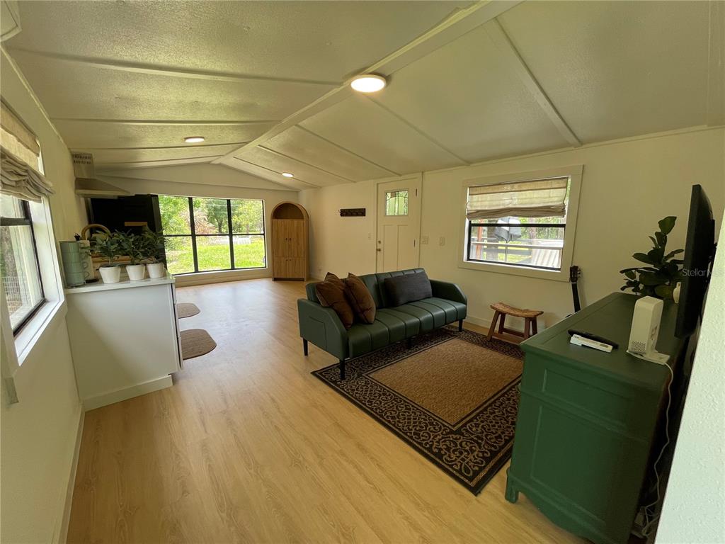A living room features light wood-look flooring, a green sofa, and a large window — 9285 LUNA DRIVE, ST CLOUD, FL
