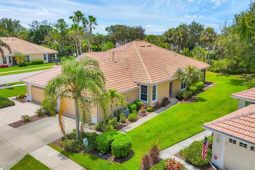 An aerial view of a tan single-story house with a tiled roof and palm trees — 4841 WHISPERING OAKS DRIVE, NORTH PORT, FL