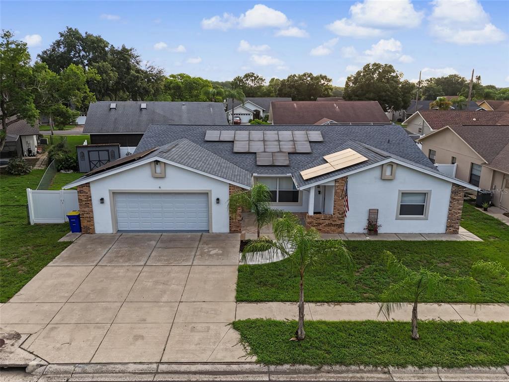 An aerial view of a single-story house with a garage, solar panels, and palm trees — 4607 SAWGRASS BOULEVARD, NEW PORT RICHEY, FL