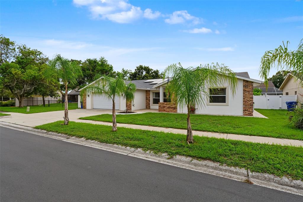 A single-story house with a white exterior, brick accents, a garage, and three palm trees — 4607 SAWGRASS BOULEVARD, NEW PORT RICHEY, FL
