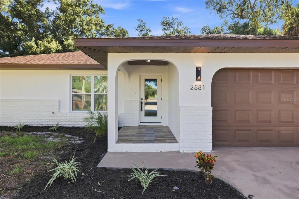 The exterior of a single-story house features a white brick facade, brown garage, and entryway — 2881 POPPY ROAD, VENICE, FL