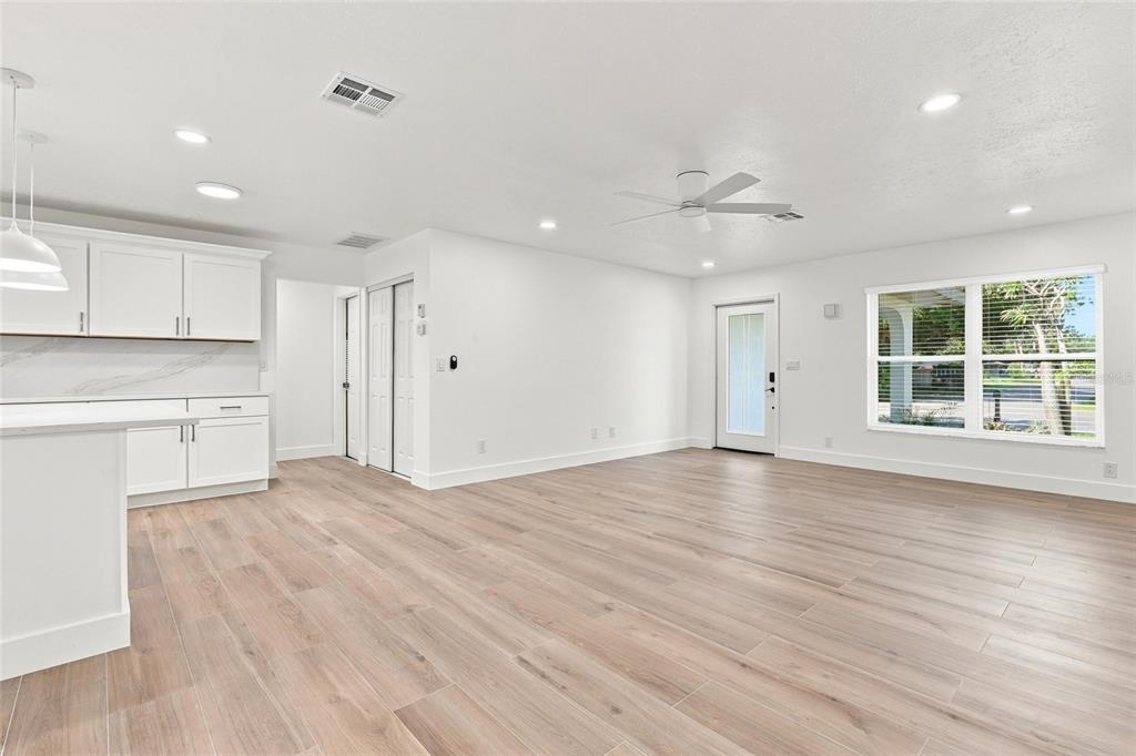 A bright, open-concept kitchen and living area featuring white cabinetry and light wood-look flooring — 2881 POPPY ROAD, VENICE, FL