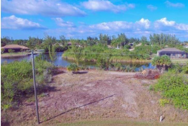 An elevated view of a vacant, grassy lot bordering a small pond with surrounding houses — 15642 APPLEWHITE CIRCLE, PORT CHARLOTTE, FL
