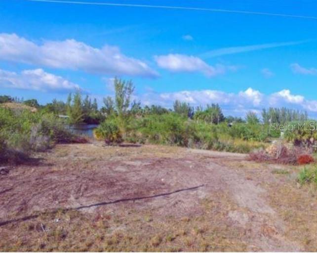 A vacant, cleared lot with sparse vegetation leads to a small body of water — 15642 APPLEWHITE CIRCLE, PORT CHARLOTTE, FL