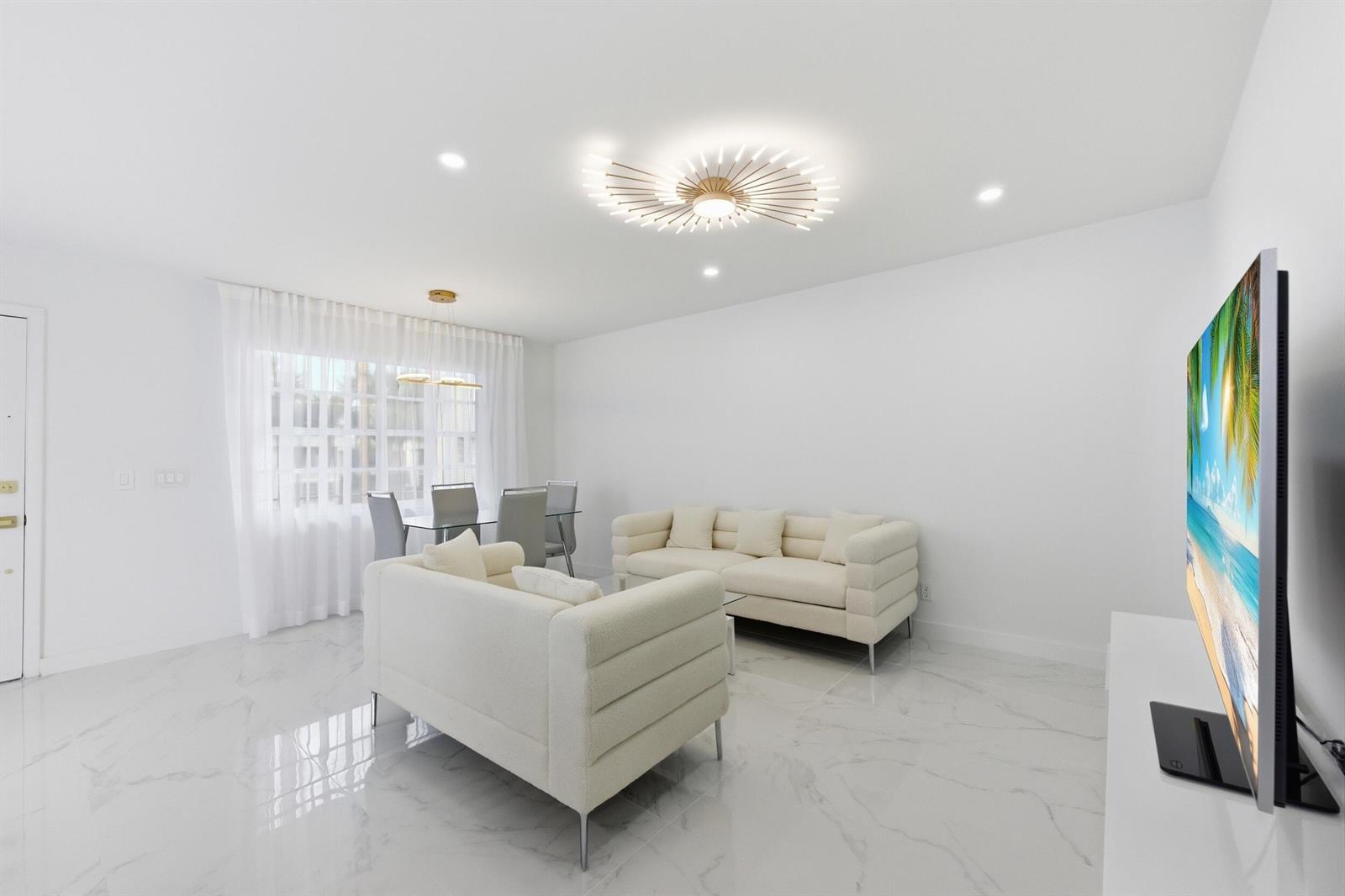 A bright living and dining area features white walls, marble floors, and modern light fixtures — 618 Normandy M, Delray Beach FL 33484, DELRAY BEACH, FL