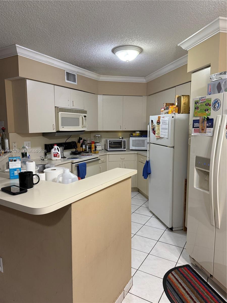 A kitchen features white cabinets, white appliances, a breakfast bar, and tiled flooring — 4677 NW 9th St # 106, Miami FL 33126, MIAMI, FL