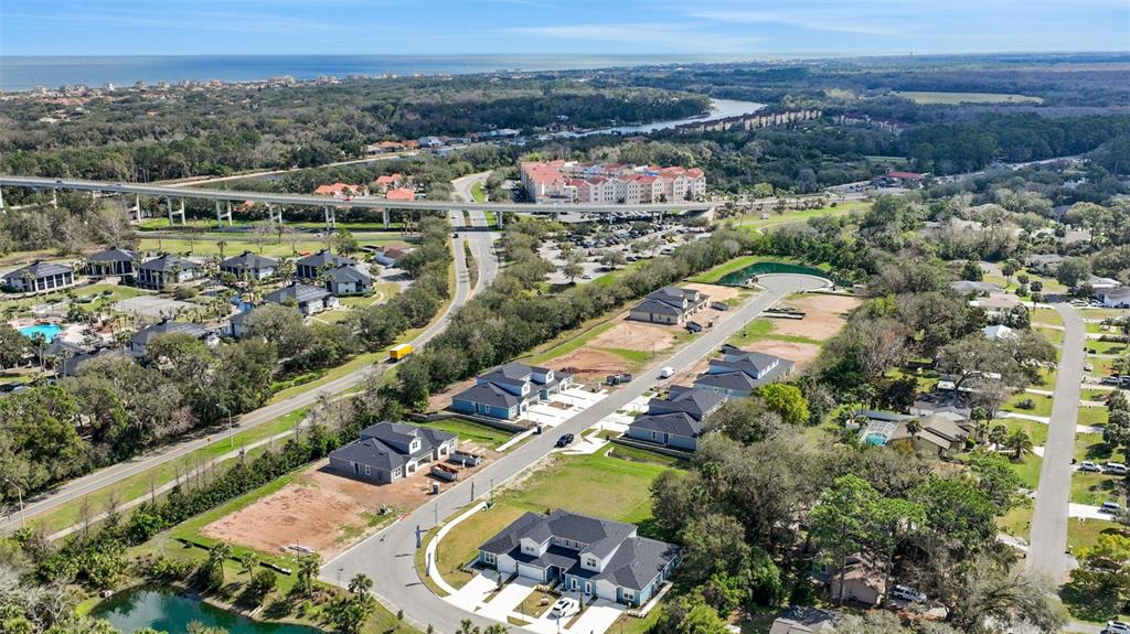 An aerial view shows a residential neighborhood with new houses under construction near a highway — 227 MISTY HARBOR TRACE, PALM COAST, FL