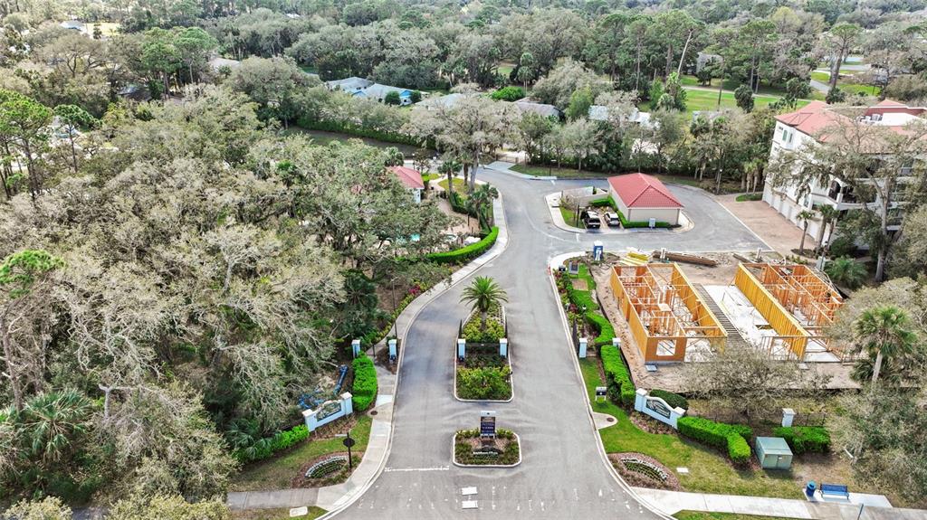 An aerial view shows a gated community entrance with a construction site and trees — 227 MISTY HARBOR TRACE, PALM COAST, FL