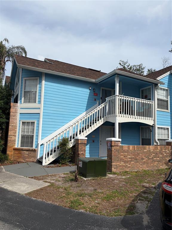 A two-story blue apartment building features an exterior staircase leading to an upper balcony — 2717 N POINCIANA BOULEVARD UNIT 169, KISSIMMEE, FL