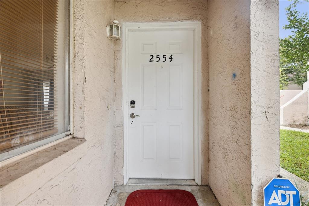 A white front door with the number 2554 is set in a stucco exterior wall — 2554 LAKEWAY BRANCH DRIVE UNIT 3001, ORLANDO, FL