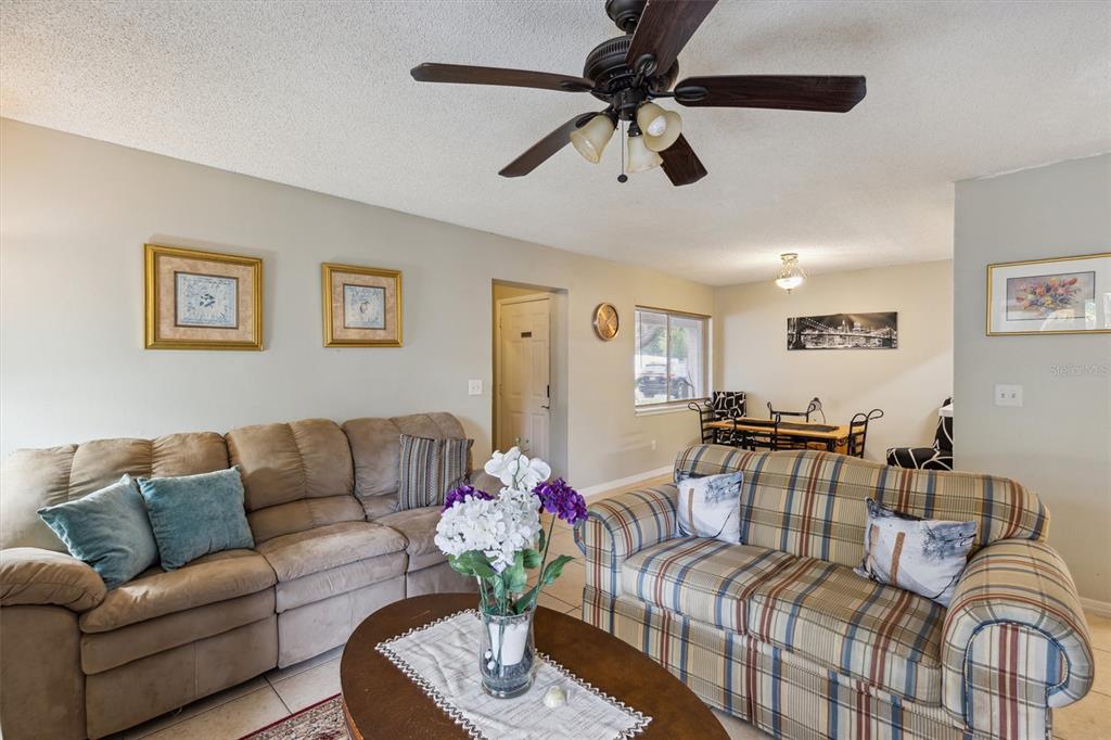 A living room features a tan sofa, a plaid loveseat, and a ceiling fan — 2554 LAKEWAY BRANCH DRIVE UNIT 3001, ORLANDO, FL