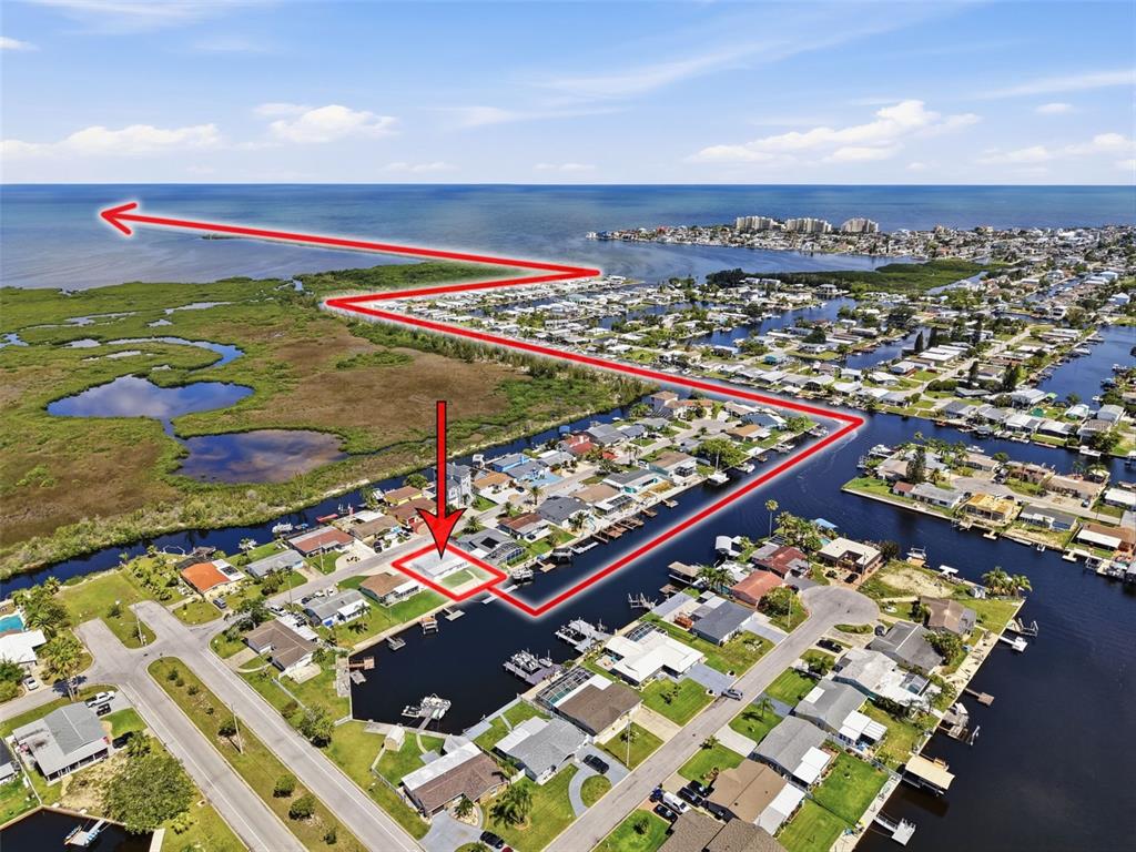 An aerial view shows a waterfront residential property with a red outline and directional arrow — 12800 5TH ISLE, HUDSON, FL