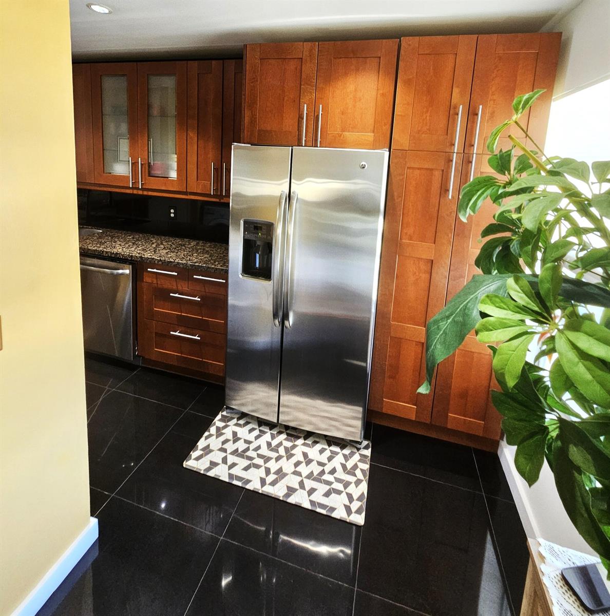 A kitchen features wood cabinets, stainless steel appliances, granite countertops, and black tile flooring — 1141 Violet Terrace # 201, Delray Beach FL 33445, DELRAY BEACH, FL