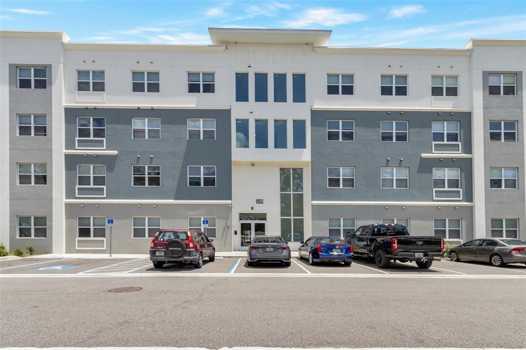 A multi-story apartment building exterior with a parking lot in the foreground — 1220 SOUTHSTATION PLACE UNIT 207, ORLANDO, FL
