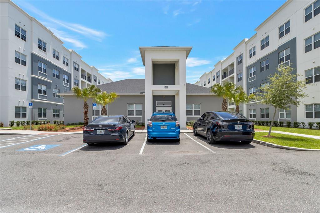 A three-story apartment complex exterior with a central clubhouse and three parked cars — 1220 SOUTHSTATION PLACE UNIT 207, ORLANDO, FL