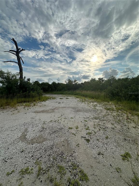 A gravel path leads through a grassy, undeveloped lot toward a line of trees — 4362 KERRIGAN CIRCLE, PORT CHARLOTTE, FL