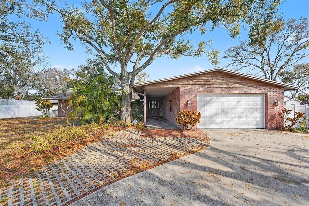 A single-story brick house features a front-facing garage, a covered entryway, and a large tree — 5967 102ND AVENUE N, PINELLAS PARK, FL