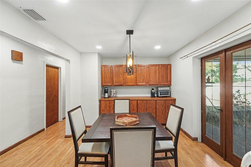 A dining room features a wooden table, four chairs, and oak cabinetry against the wall — 5967 102ND AVENUE N, PINELLAS PARK, FL