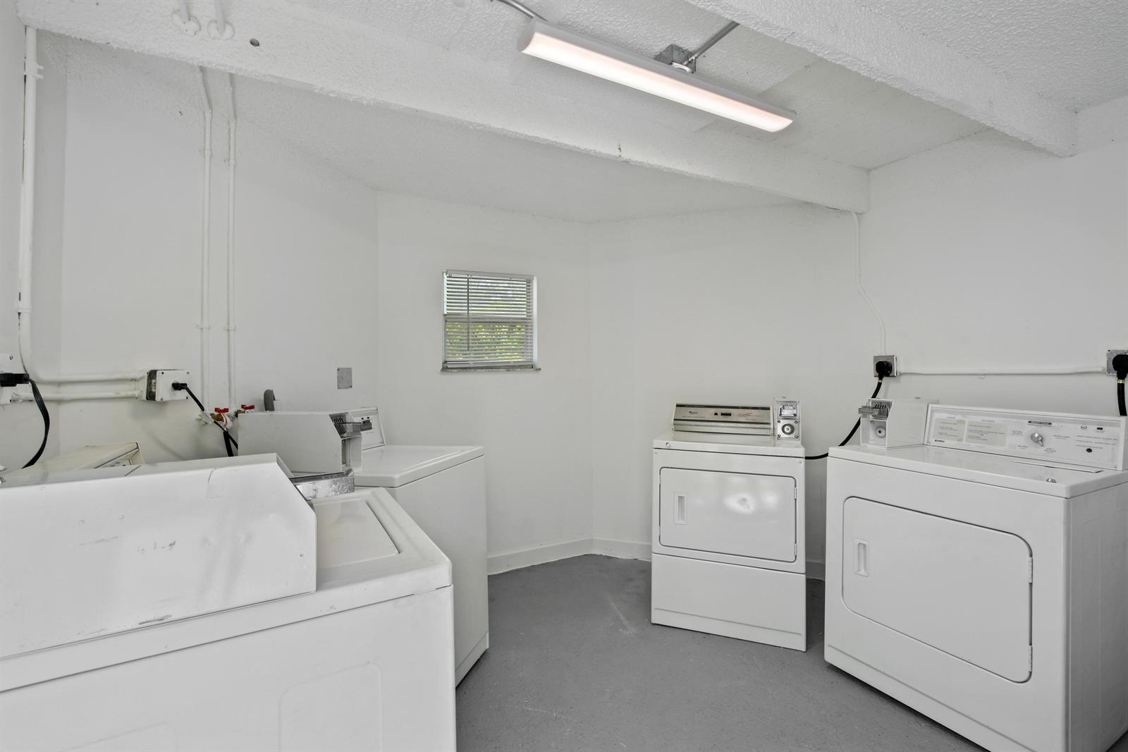 A laundry room features white walls, a gray floor, and four white coin-operated appliances — 627 Bunker Road, West Palm Beach FL 33405, WEST PALM BEACH, FL